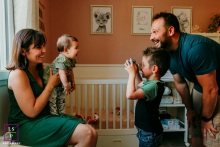 A Montpellier lifestyle scene where the older brother captures a photo of his little sister and mother, while the father watches on with affection, highlighting their joyful family interaction.