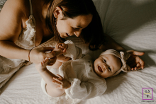 In Montpellier, France, a mother and her young daughter share a deep bond and wide smiles as they lie together on the bed.