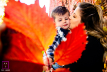 In Reno, NV, a creative fall portrait captures a mom playfully kissing her child through a leaf.