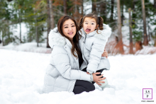 In Truckee, Nevada, a mother and daughter, both in matching powder blue winter coats, enjoy the snow as the daughter makes a goofy face.