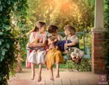 Three sisters are interacting with one another while on a porch swing in Chattanooga, Tennessee. The portrait captures their bond.