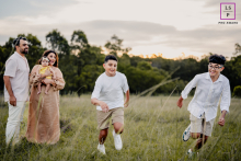 A Sydney Family Watches On As Sons Race With Delight Parents hold their daughter while they watch their sons race in a competition in Sydney, New South Wales. The photo captures a family enjoying a day of sports together.