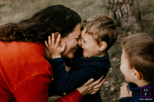 In Montpellier, a mother shares a special connection with her son as they face each other, smiling. Another boy stands nearby, watching the tender interaction, capturing a scene of family closeness.