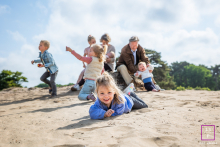 In Hilversum, The Netherlands, a lively family scene unfolds during a photo shoot—children bustling, parents embracing the joyful chaos. The candid energy highlights authentic family life, full of laughter and connection.