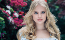 In Liverpool, UK, a young woman looks at the camera while standing in a secret garden, tucked within a city park’s lush surroundings.