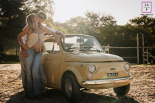 In Poleymieux-au-Monts-d'Or, Rhône, a pregnancy portrait captures a La Dolce Vita scene by an old small car at sunset.