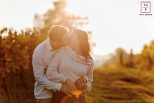 In Morat, Switzerland, a couple stands in the vineyards at sunset, warmly backlit by golden light that softly envelops them.