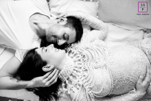In a Ravenna studio in Italy, an artistic black-and-white maternity portrait shows a woman wearing pearls, lying indoors, their heads positioned in a yin-yang pose.
