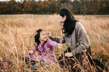 At Waveny Park in New Canaan, mom and daughter smile together while surrounded by tall, dry grass.