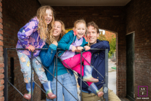 A family smiles under a shelter on a rainy street in Utrecht, The Netherlands, enjoying their fun, impromptu photoshoot.