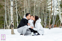 Parents happily kissing their children while playing together outdoors in the fresh winter snow in Truckee, CA.