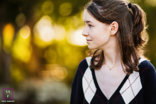 A teen girl stands in profile among leafy trees in Mountain View, California, softly lit by afternoon sun, reflecting a calm and contemplative mood.