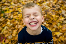 Surrounded by autumn leaves in St Albans, this child throws his whole face into an unstoppable grin that feels wonderfully contagious. The close framing and sea of golden color keep the energy playful, spontaneous, and completely centered on joy.