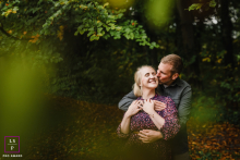 Couple Shares Intimate Embrace Hidden In Deep Foliage At Schloss Heeren In Kamen, Germany Portrait Surrounded by deep green foliage at Schloss Heeren in Kamen, this couple disappears into their embrace with effortless tenderness. The foreground leaves soften the frame beautifully, making the affection feel private, intimate, and hidden from the world