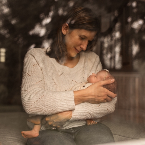 This lifestyle portrait captures a heartfelt gaze in Chagrin Falls, OH, as a mother gazes lovingly at her precious newborn baby girl