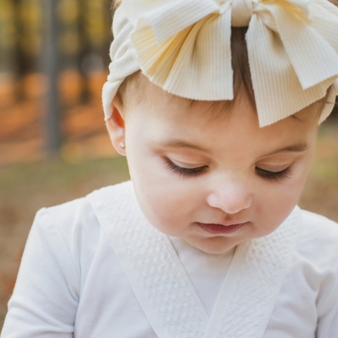 Enchanting Lifestyle Portrait: Young Girl's Delightful Charm Shines in New Jersey's Heartwarming Family Portrait This captivating lifestyle portrait, taken in New Jersey, United States, showcases a young girl adorned with a charming white bow on her head
