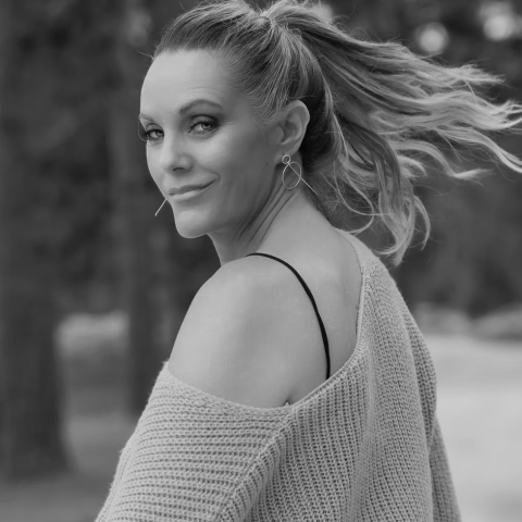 Kansas City photographer Andrea DeLong poses outdoors in a natural setting