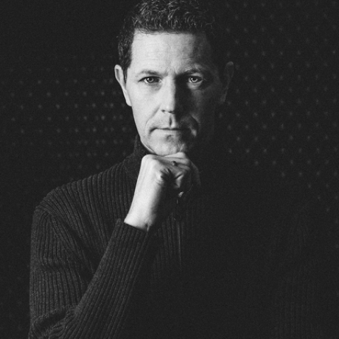 Black and white studio portrait of Andreas Pollok, an accomplished lifestyle photographer based in Baden-Württemberg, Germany, posing for the camera.